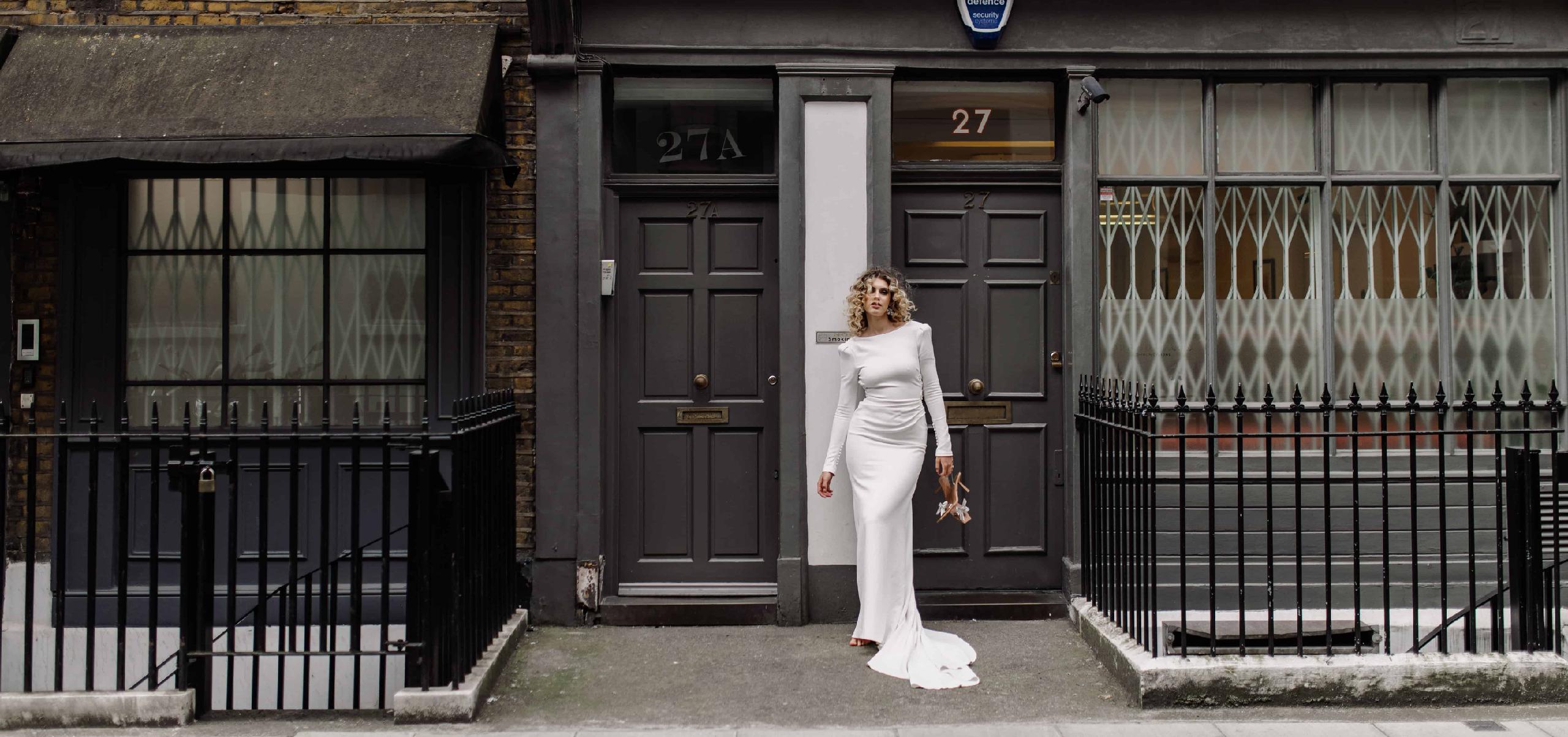 nevesta stojaca v dlhých šatách v budapešti, v pozadi stoje monumentálna osvetlená budova