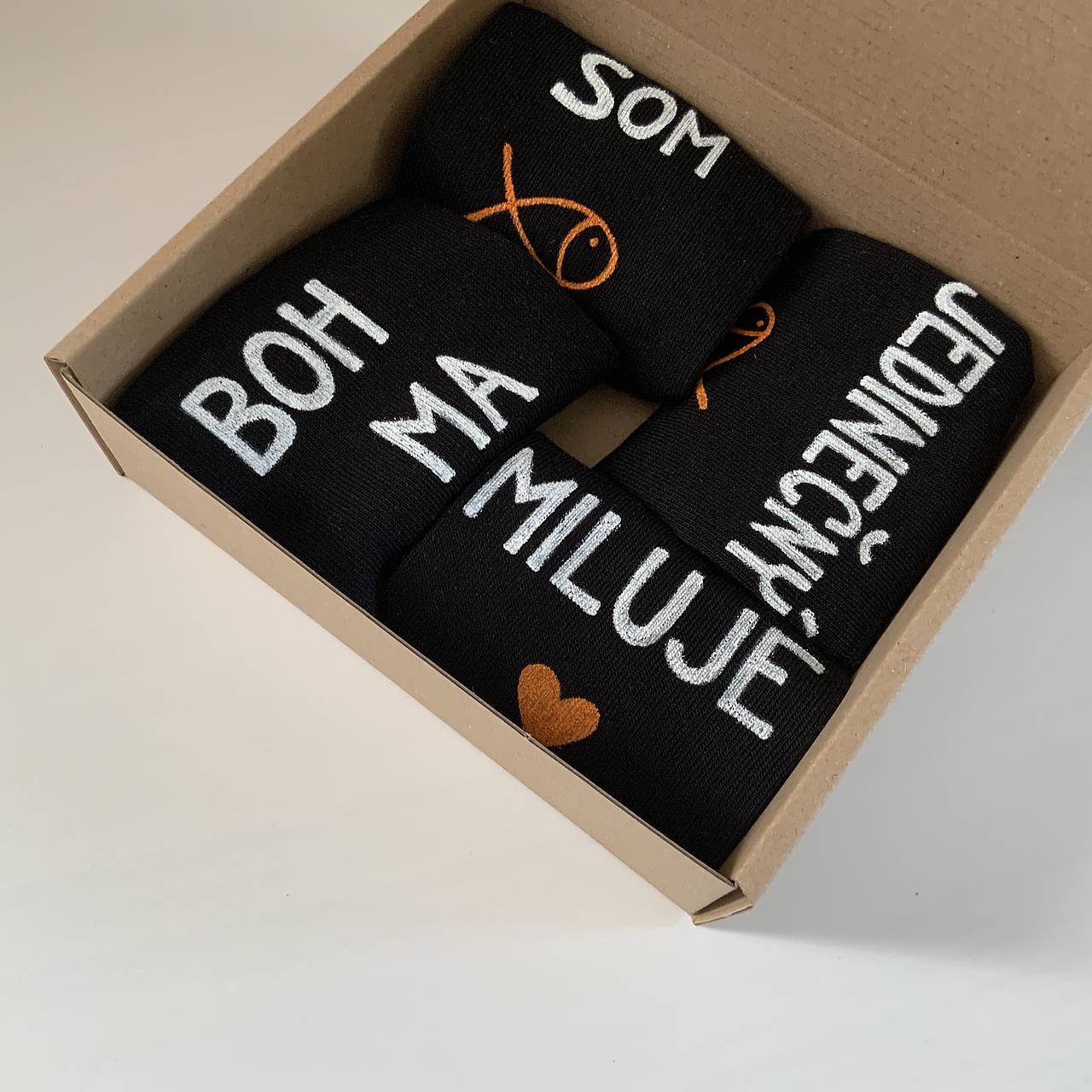 Sada maľovaných čiernych ponožiek s nápismi ”Boh ma miluje" a "Som jedinečný”