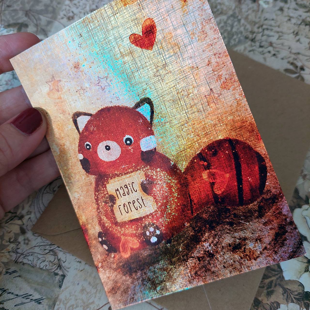 Červená panda s  obľúbenou knižkou - trblietavá holografická pohľadnica s obálkou