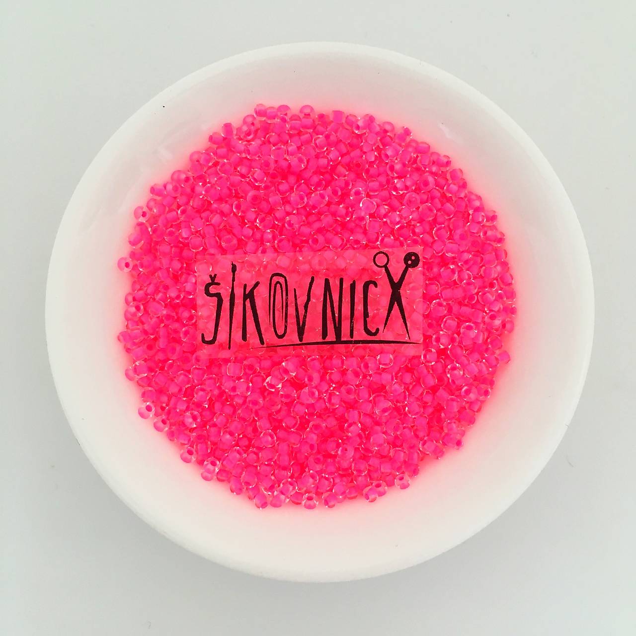 10/0 rokajl PRECIOSA  - 50 g (774 priehľadná s neónovo ružovým prieťahom)