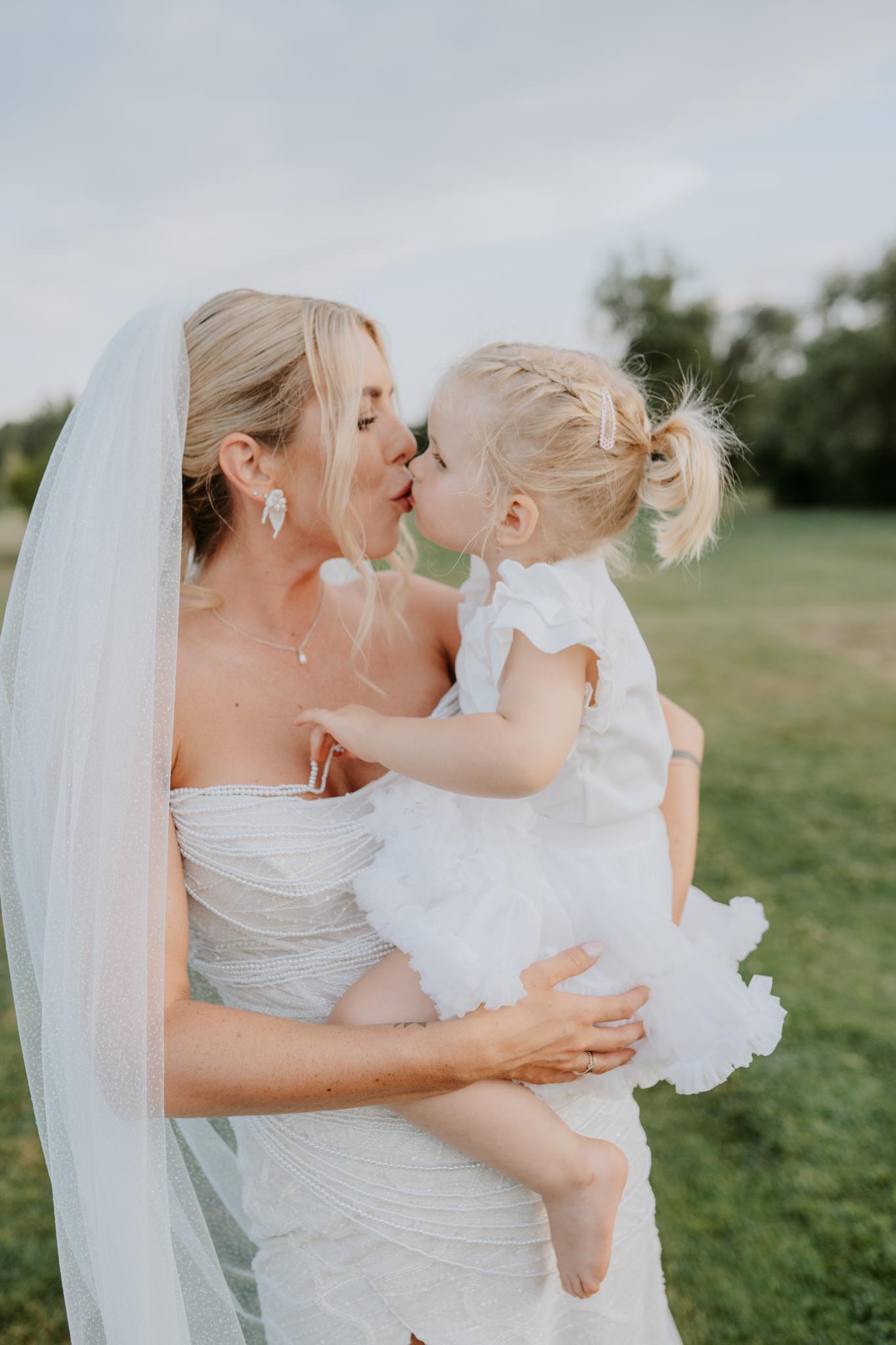 foto nevesty s dlhým závojom, ktorá má na rukách malé dievčeatko