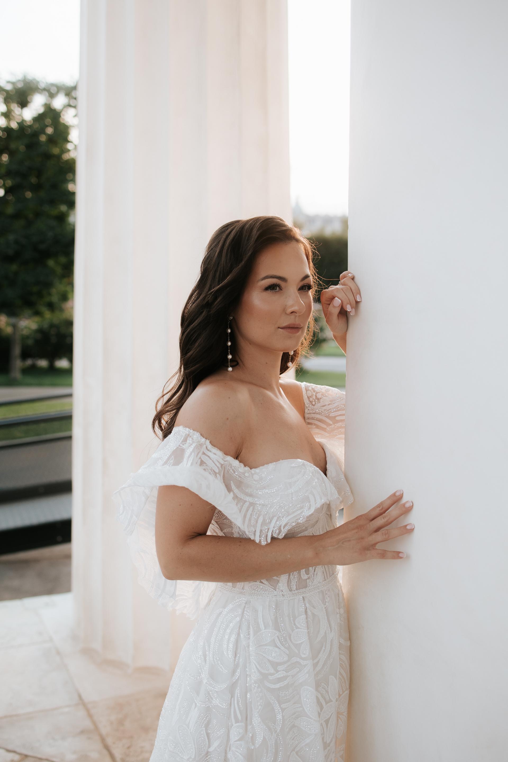 Tmavovlasá nevesta stojaca pri múre a hľadiaca do diaľky