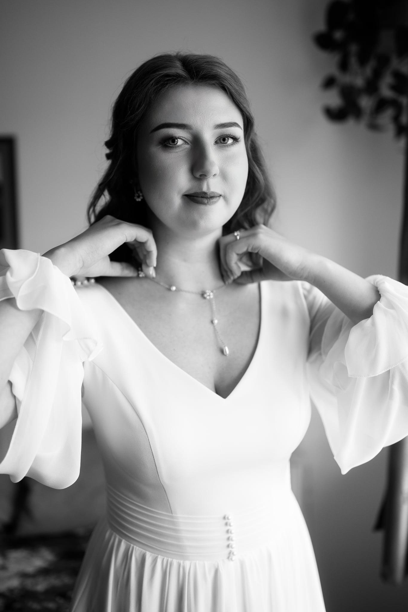 čiernobiela fotografia nevesty v jednoduchých šatách, ktorá ma na krku retiazku