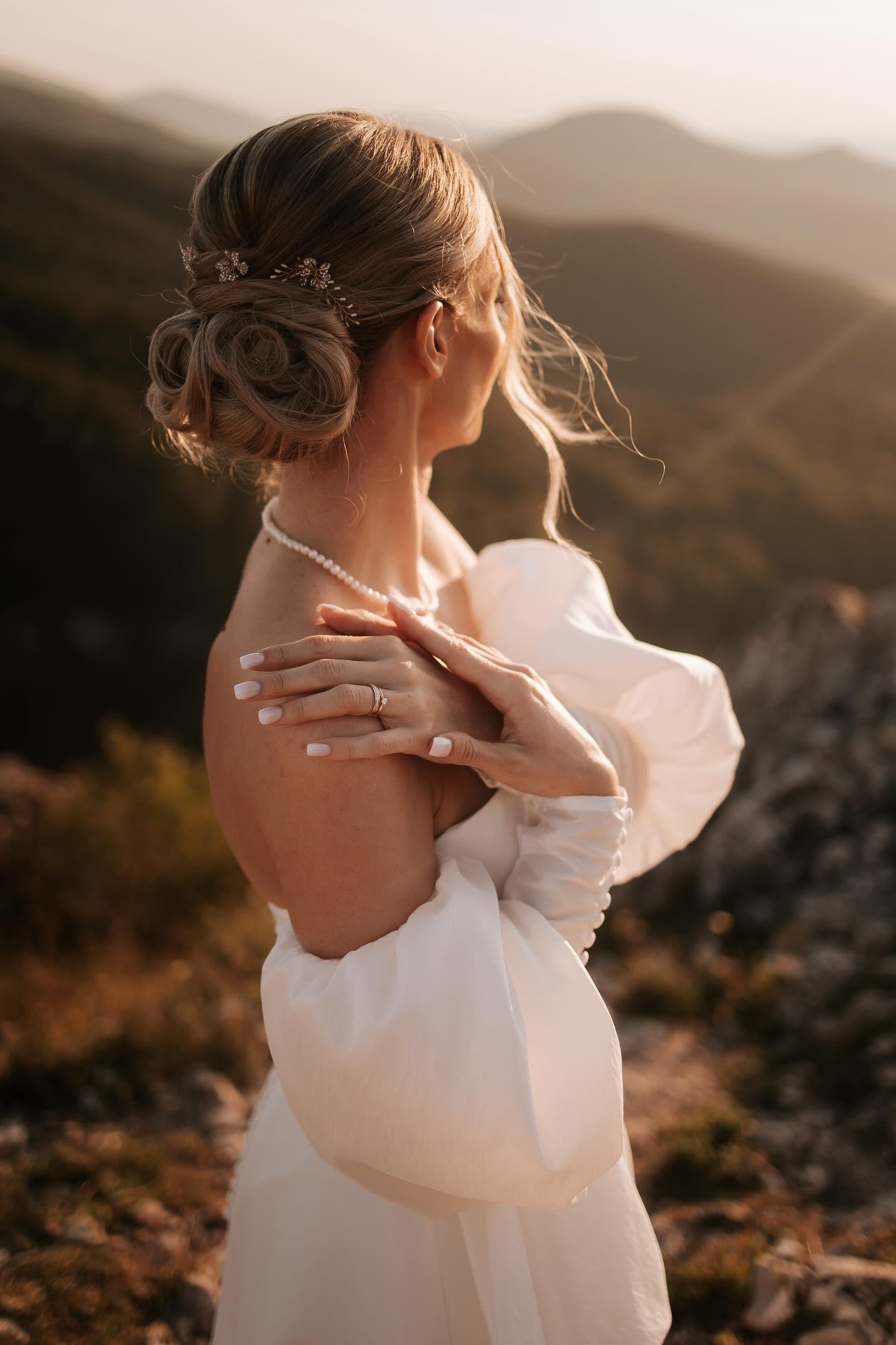 „Nevesta so zapleteným svadobným účesom a jemnými vlasenkami do vlasov, svadobné doplnky v prírodnom prostredí.“