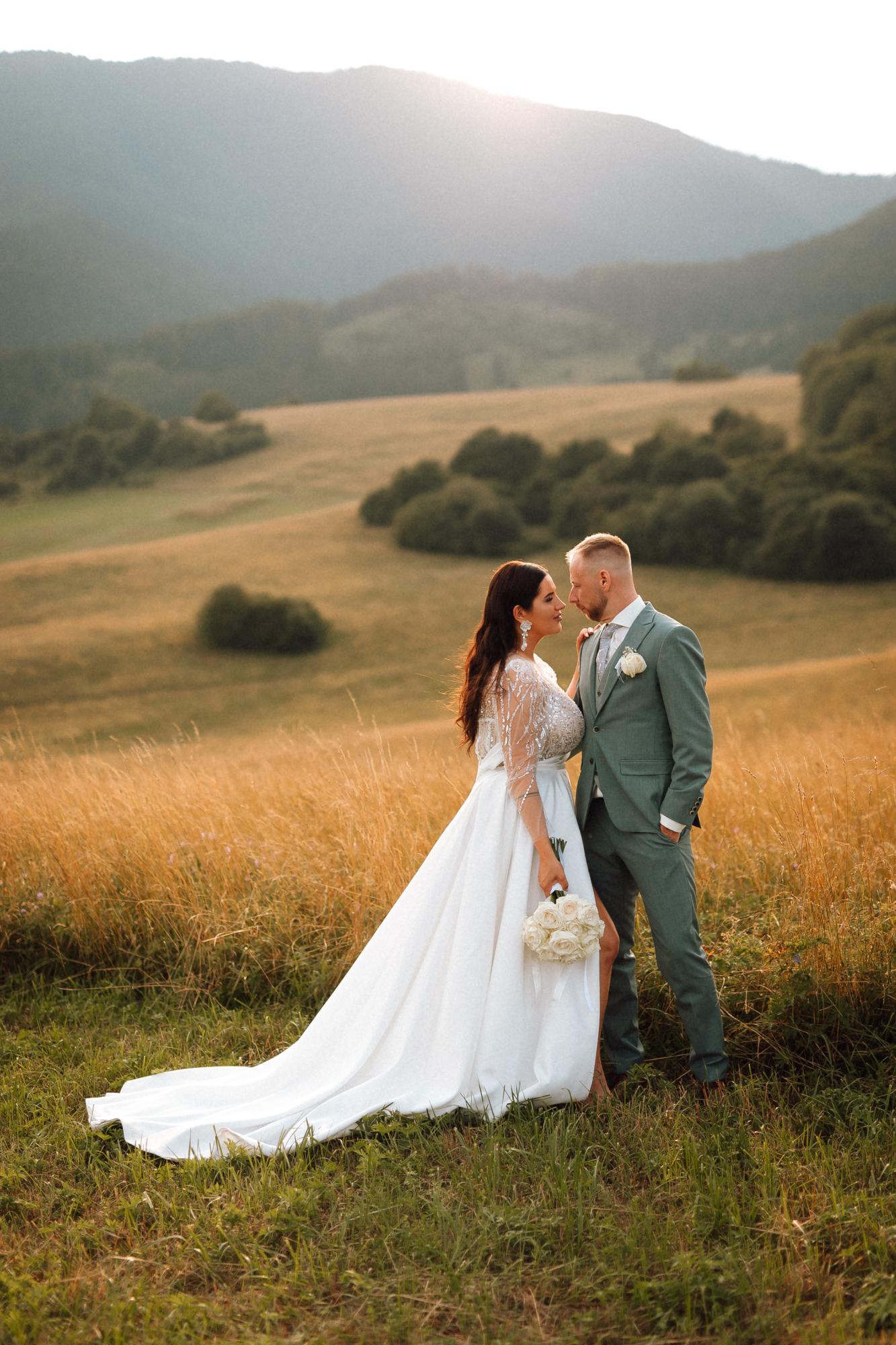 Nevesta a ženích pri západe slnka v prírode, svadobné fotenie v romantickom prostredí.