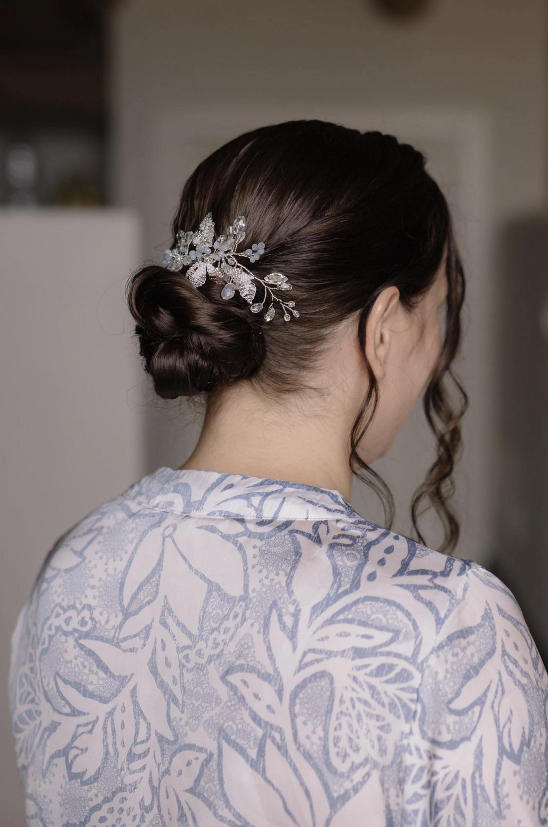 Detail svadobného účesu zozadu s hladkým drdolom a jemnou vlasovou ozdobou z kryštálov a lístkov.