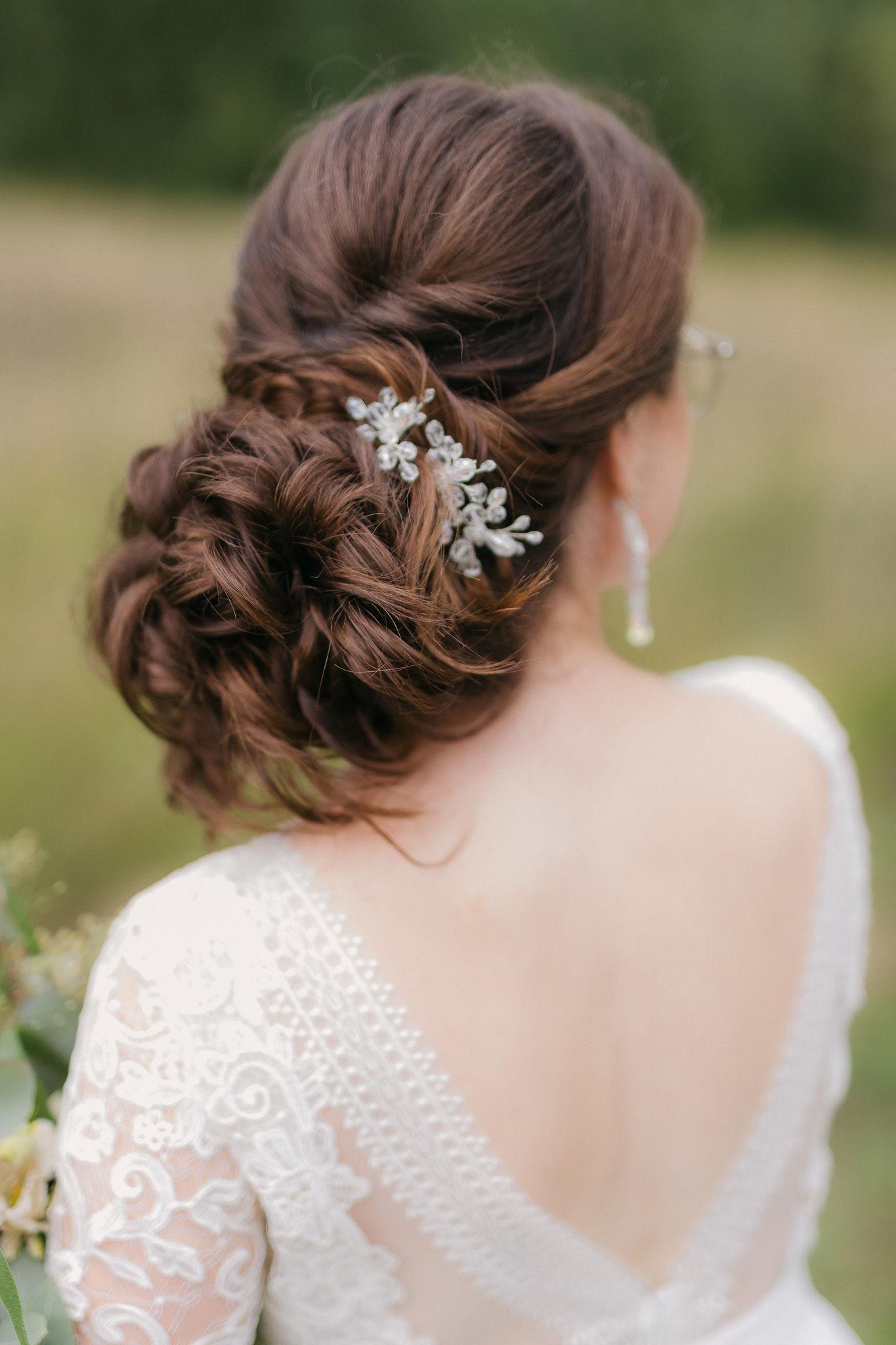 Detail svadobného účesu zozadu s nízkym drdolom a jemnou vlasovou ozdobou z kryštálov.